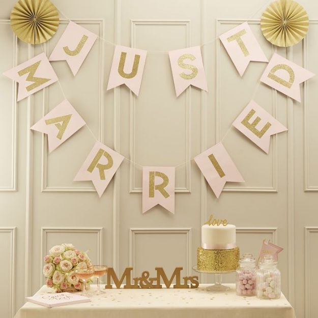 Banner i kraftig karton med bogstaver i guldglimmer med teksten "Just Married"